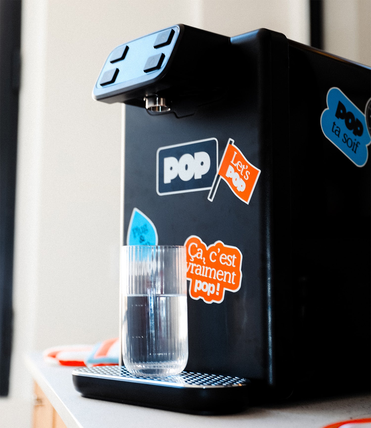 Fontaine à eau POP personnalisée, en train de remplir un verre d’eau dans un espace de travail.